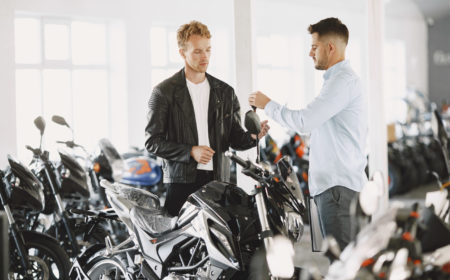 Man choosed motorcycles in moto shop. Guy in a black jacket. Manager with client.